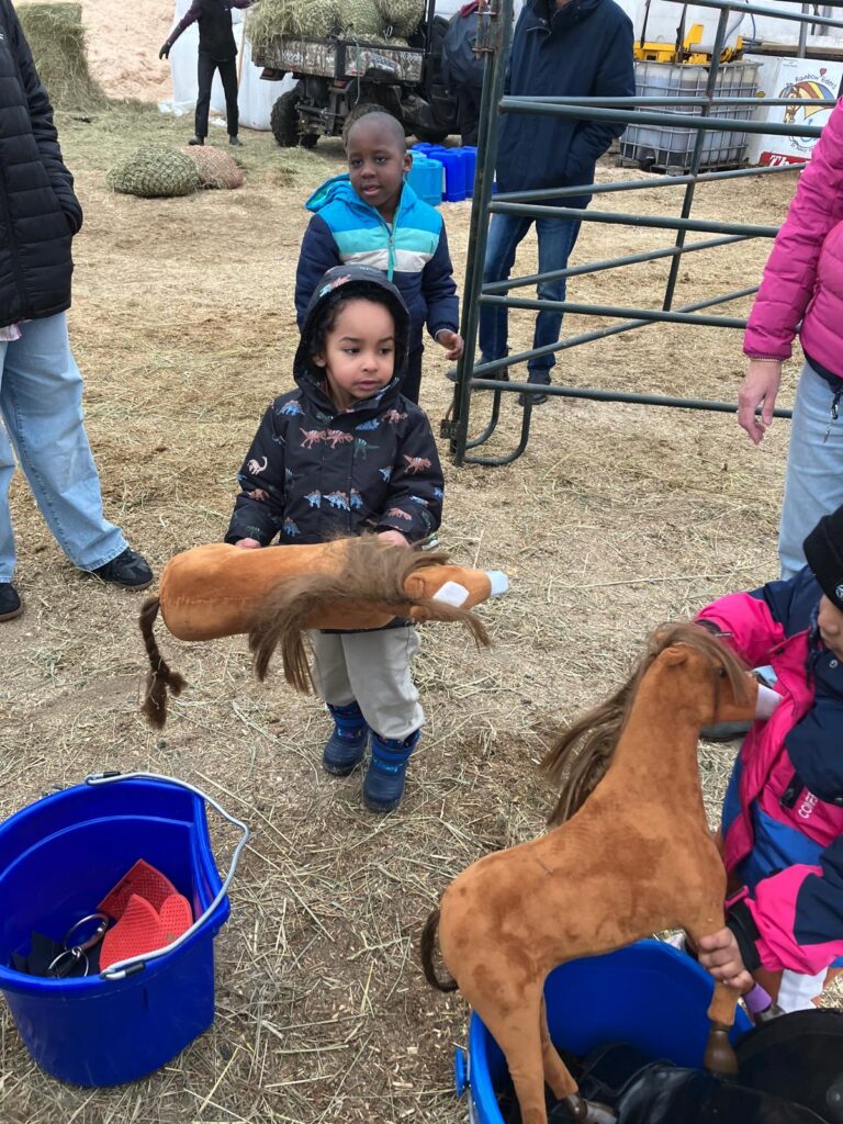 HIPPY program children playing with stuffed horses outdoors at Rainbow Riders NL Rainbow Connection event